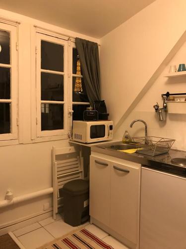 une cuisine avec un évier et un micro-ondes dans l'établissement Studio Passy - Tour Eiffel, à Paris