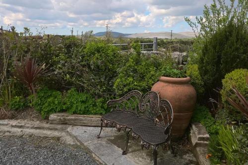 a bench and a large vase in a garden at The Burren Art Gallery built in 1798 in Tubber