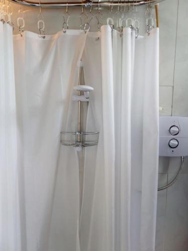 a bathroom with white shower curtains in a room at The Burren Art Gallery built in 1798 in Tubber
