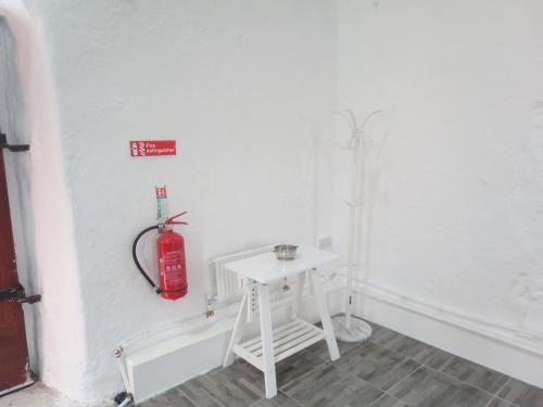 een witte kamer met een brandblusser aan de muur bij The Burren Art Gallery built in 1798 in Tubber