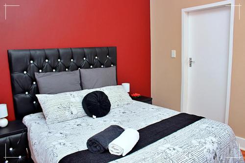 a bedroom with a black bed with a red wall at THE GLOBAL LINK HUB in Pretoria