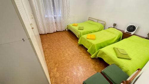 two beds in a room with green sheets at da Lilia in Salute&Bellezza in Monfalcone