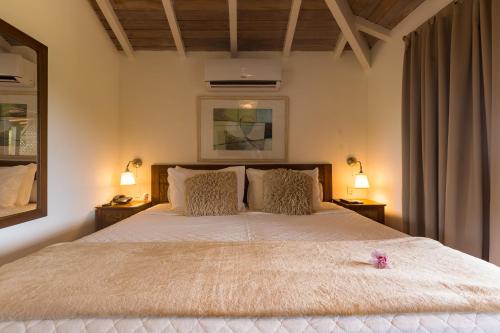a bedroom with a large white bed with two lamps at La Pedrera Small Hotel & Spa in Búzios