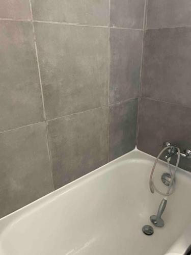 La salle de bains est pourvue d'une baignoire blanche et d'un mur en carrelage. dans l'établissement Appartement rénové au Penon, à Seignosse