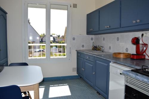 una cocina con armarios azules y una ventana en L'Estran - maison sur la digue avec vue mer, en Courseulles-sur-Mer