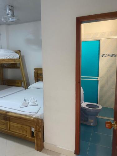a room with two beds and a bathroom with a toilet at Sweet Dreams Necocli in Necoclí