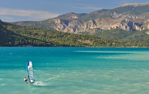 a person is windsurfing in the water on a lake at La maison des collines in Allemagne-en-Provence