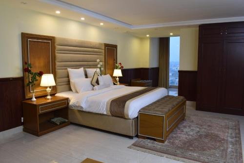 ein Schlafzimmer mit einem großen Bett und einem großen Fenster in der Unterkunft Al Nafoura Hotel in Lahore
