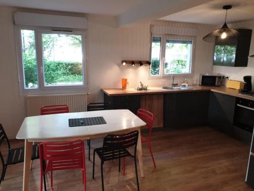 eine Küche mit einem weißen Tisch und roten Stühlen in der Unterkunft 62 m2 Rez de jardin, terrasse , 6 lits et parking in Annecy