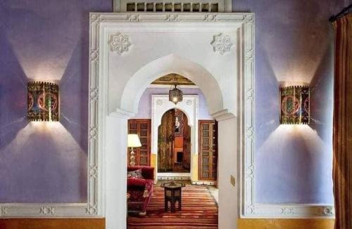 an archway in a living room with purple walls at DAR ELHADIR in Tozeur
