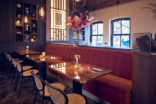 a restaurant with a red bench and tables and chairs at The Yard hotel Noordkade in Veghel
