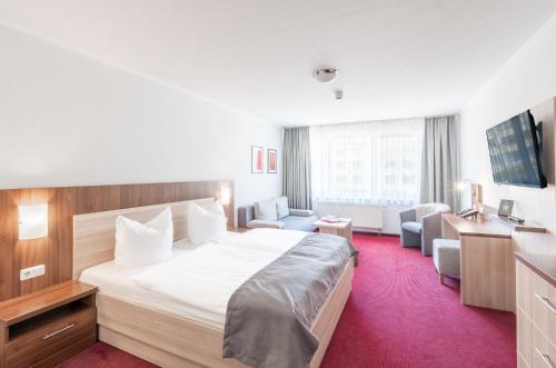 a hotel room with a large white bed and chairs at Sporthotel Neuruppin in Neuruppin