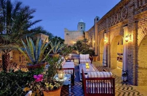 un patio al aire libre con mesas, sillas y plantas en DAR ELHADIR en Tozeur