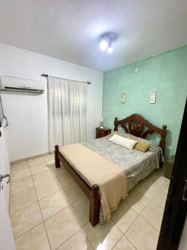 1 dormitorio con cama y pared verde en Departamento Perú en Corrientes