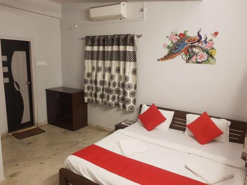 Schlafzimmer mit einem Bett mit roten Kissen und einem Fenster in der Unterkunft Hotel Trisha Residency in Lonavla