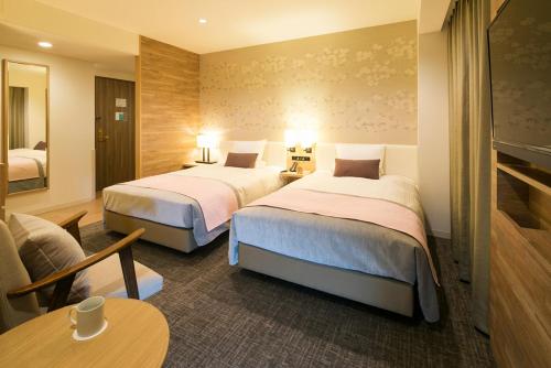 una camera d'albergo con due letti e un tavolo di JR-East Hotel Mets Kitakami a Kitakami
