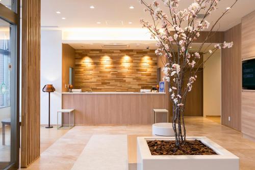 a lobby with a vase with a tree in it at JR-East Hotel Mets Kitakami in Kitakami