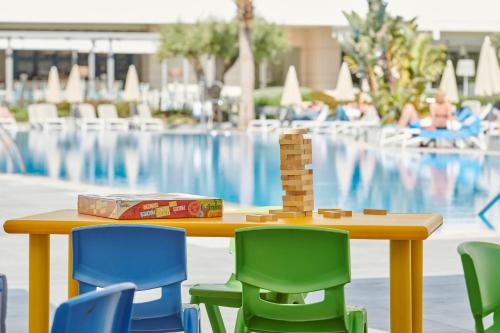 a table with chairs and a toy tower in front of a pool at Hipotels Gran Playa de Palma in Playa de Palma