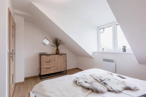a white bedroom with a bed and a dresser at Na NEBEsích in Olomouc