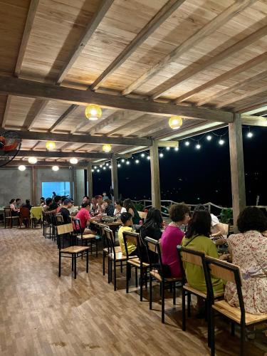 a group of people sitting at tables in a restaurant at Chipau Homestay Trạm Tấu in Cham Ta Lao
