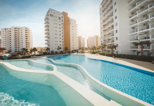 a large swimming pool with buildings in the background at Spacious One Bedroom Apartment in Caesar Resort & SPA, Long Beach in Perivolia tou Trikomou