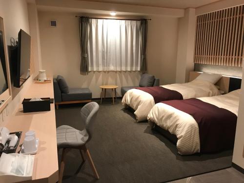 a hotel room with two beds and a television at Aizu Tsuruya Hotel in Aizuwakamatsu
