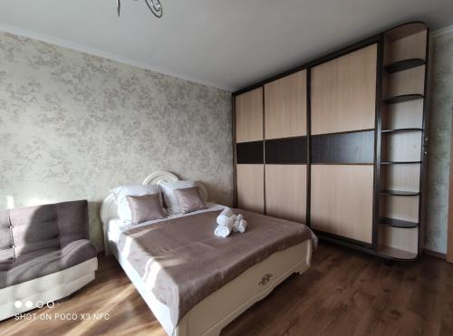 a bedroom with a large bed and a chair at Уютная однокомнатная квартирка, в тихом спальном районе, недалеко от Аэропорта in Almaty