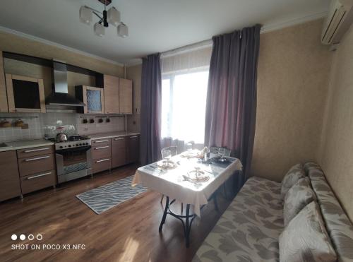 Уютная однокомнатная квартирка, в тихом спальном районе, недалеко от Аэропорта في ألماتي: مطبخ مع طاولة مع كؤوس للنبيذ عليه