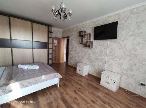 a bedroom with a bed and a flat screen tv at Уютная однокомнатная квартирка, в тихом спальном районе, недалеко от Аэропорта in Almaty