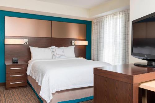 pokój hotelowy z łóżkiem i telewizorem z płaskim ekranem w obiekcie Residence Inn by Marriott Grand Rapids West w mieście Grand Rapids