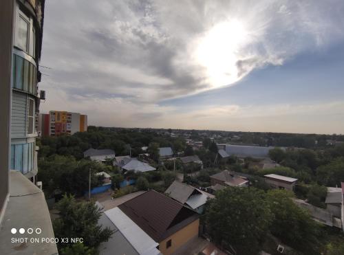 una vista de una ciudad desde un edificio con el sol en el cielo en Уютная однокомнатная квартирка, в тихом спальном районе, недалеко от Аэропорта, en Almaty
