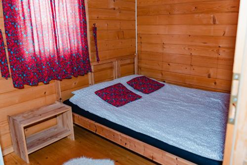 a small room with a bed in a wooden cabin at NOVMI - Domki letniskowe 