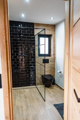 a bathroom with a black brick wall and a tub at NOVMI - Domki letniskowe 