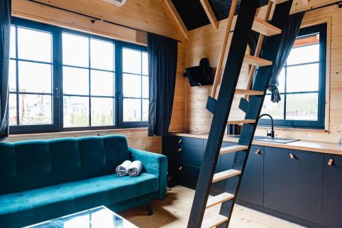 a living room with a green couch and a ladder at NOVMI - Domki letniskowe 