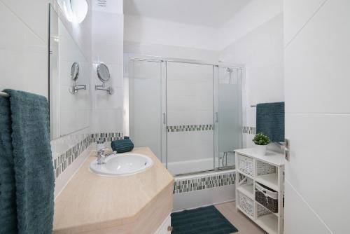Un baño blanco con lavabo y ducha. en Villa Janeca, en Albufeira