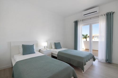 Una habitación de hotel con dos camas y balcón. en Villa Janeca, en Albufeira