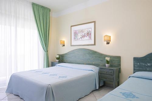 a bedroom with two beds and a table and a window at Hotel Maria Rosaria in Orosei