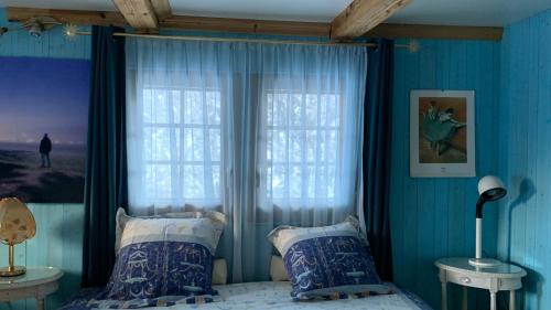 a bedroom with blue walls and a bed with a window at Les Quatre Saisons - balcon et jardin in Val-d'Illiez