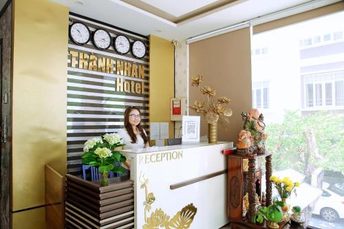 ダナンにあるThành Nhân Hotelのロビーのフロントデスクに立つ女性