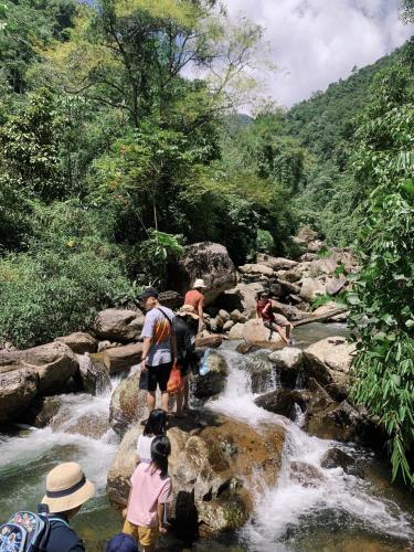 a group of people standing on rocks in a river at Chipau Homestay Trạm Tấu in Cham Ta Lao