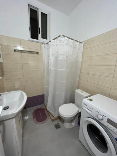 a bathroom with a toilet a sink and a washing machine at KAFUL APARTMENTS in Qeparo