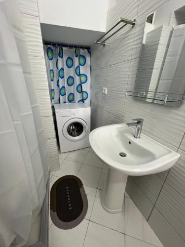 a bathroom with a sink and a washing machine at KAFUL APARTMENTS in Qeparo