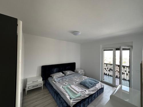 a white bedroom with a bed and a window at ShooTer Apartments in Ferizaj