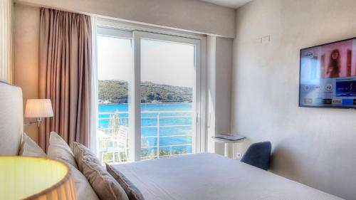 a bedroom with a large window with a view of the water at Hotel Plaza in Porto Azzurro