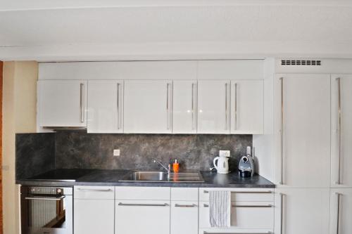 a kitchen with white cabinets and a sink at Magnifique appartement au coeur des 4 Vallées in Les Collons