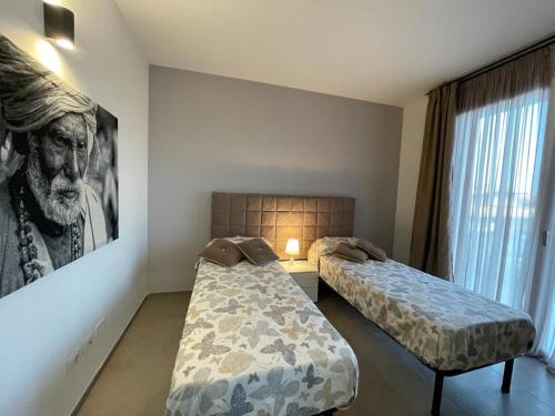 Habitación con 2 camas y una pintura en la pared. en villa polinesia 7, en Lido delle Nazioni