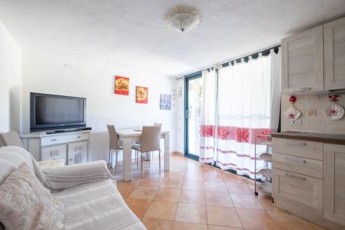 uma sala de estar com um sofá e uma mesa com uma televisão em [Mare a 4 minuti Auto]Casa/Giardino e WiFi Budoni em Budoni