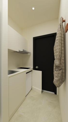a kitchen with white cabinets and a black door at Roula's house on the beach in Skiathos Town