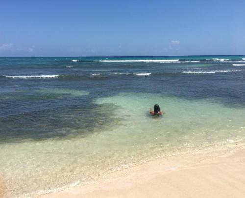 a person swimming in the ocean on a beach at African Symbol Guest House in Montego Bay
