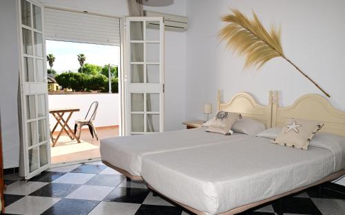a bedroom with a white bed and a palm tree at Hostal Los Rosales in Conil de la Frontera